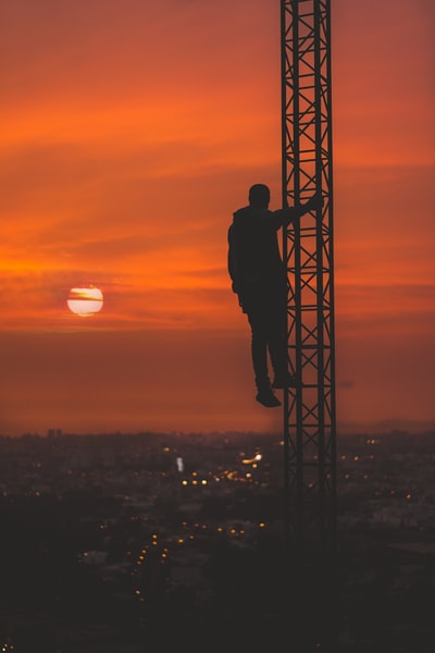 在日落轮廓的男人爬塔
